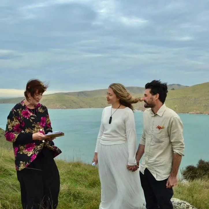 A couple at their wedding ceremony overlooking Akaroa Harbour on Banks Peninsula, native bush framing the scene