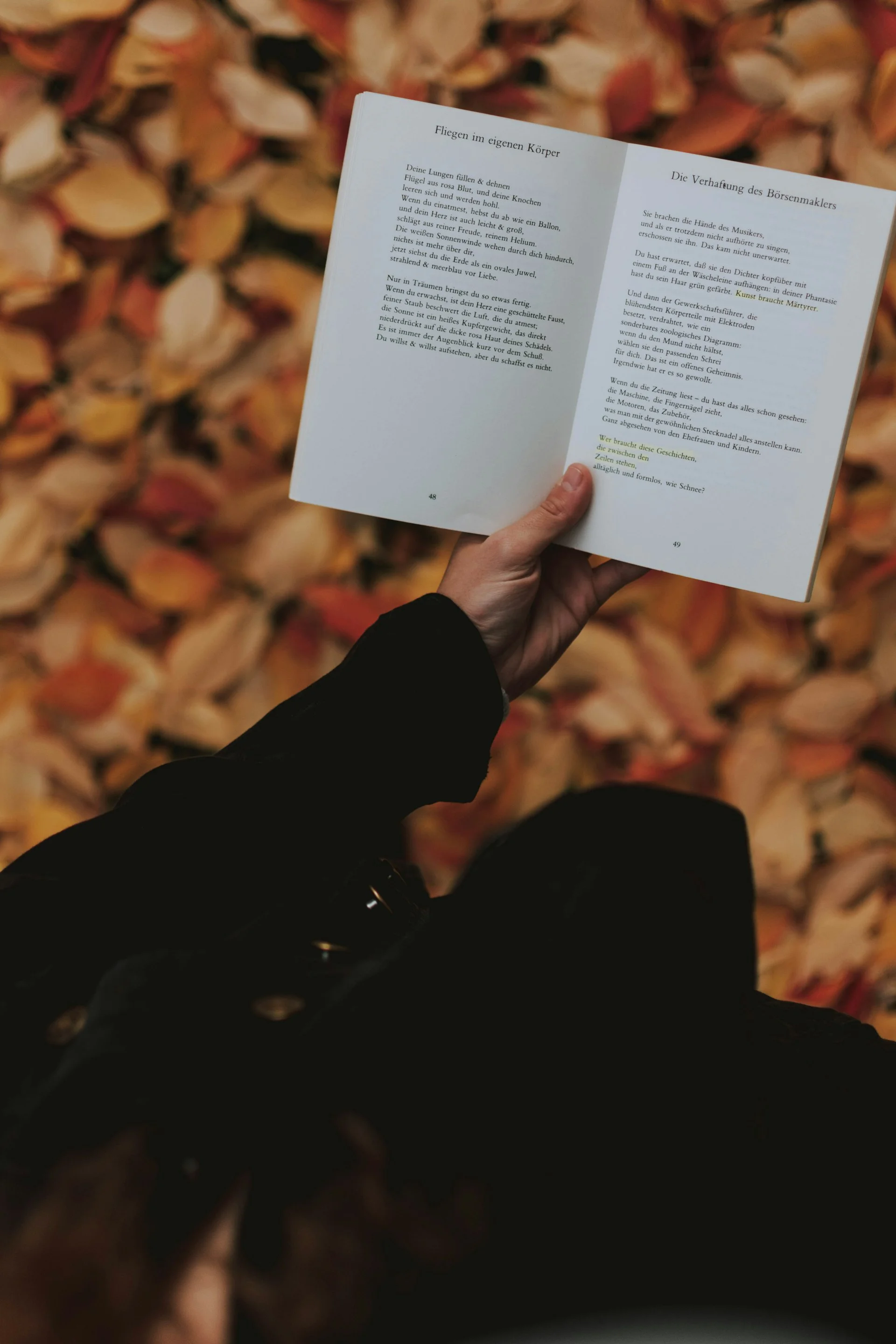 An open book with marked pages resting on a table with flowers, ceremony stationery in soft focus