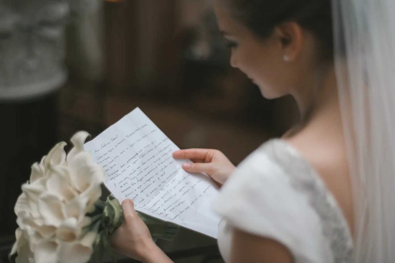 A close-up of handwritten wedding vows on cream paper, a pen resting beside them
